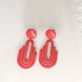 Handmade salmon pink Art Deco arch cutout polymer clay drop earrings on white display tray