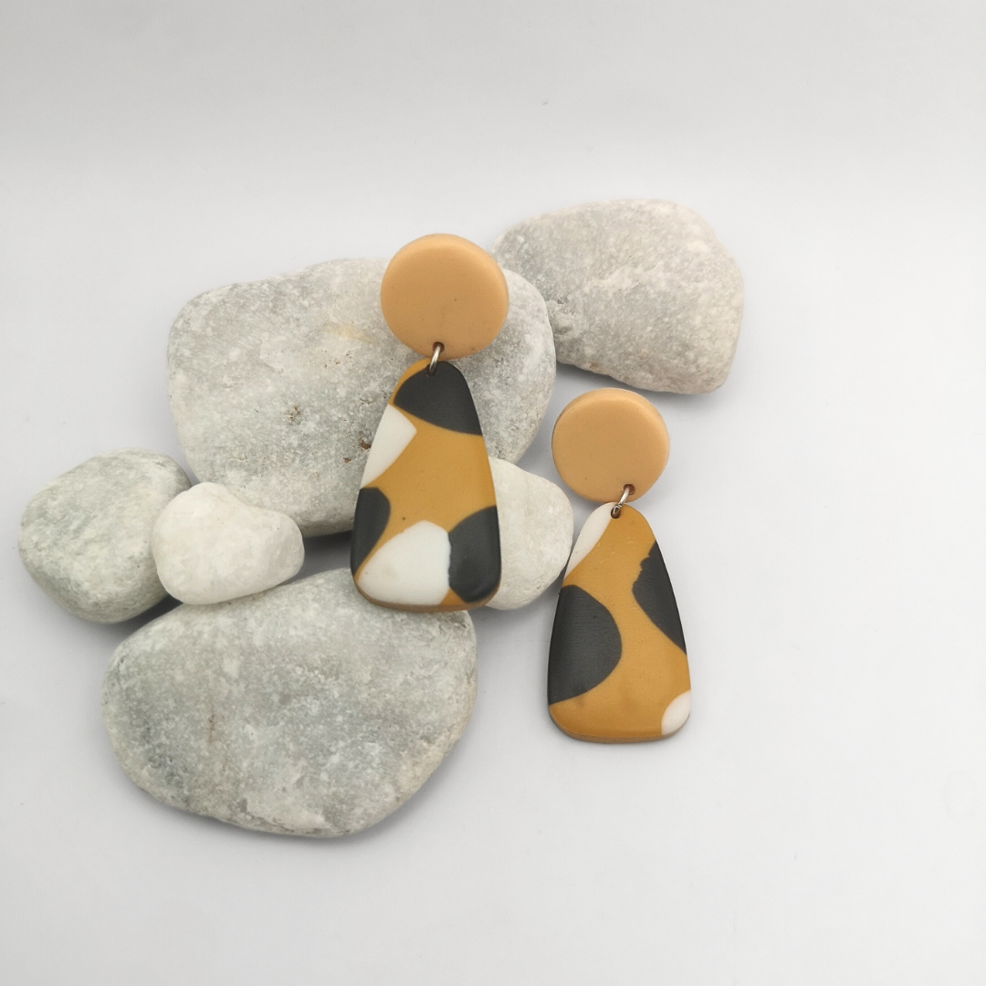Pair of earrings with brown, black, and white design on a white background