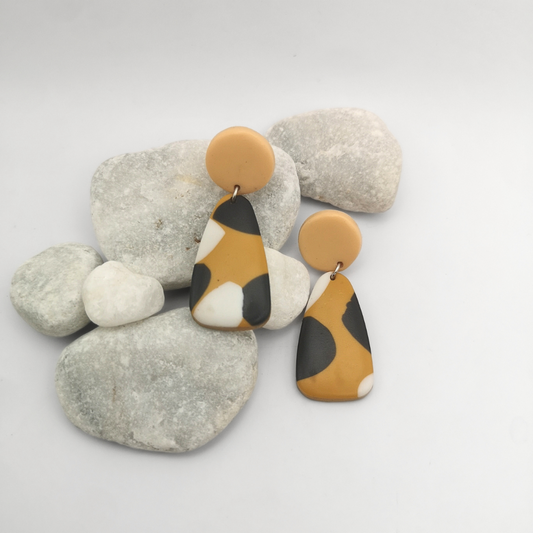 Pair of earrings with brown, black, and white design on a white background