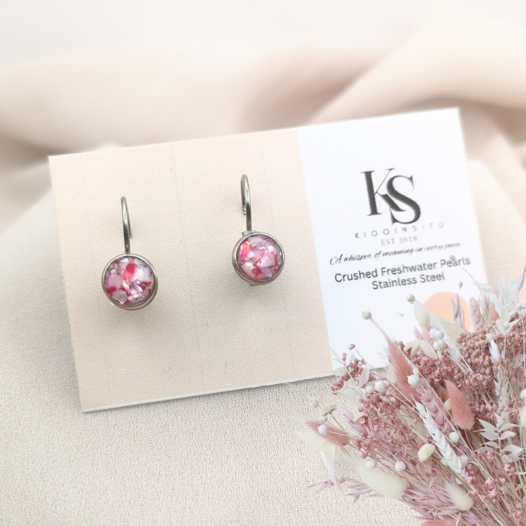Handmade with care, these 6 mm stainless steel leverback earrings feature crushed freshwater pearls in delicate pink hues, sealed beneath a clear, glass-like resin. 