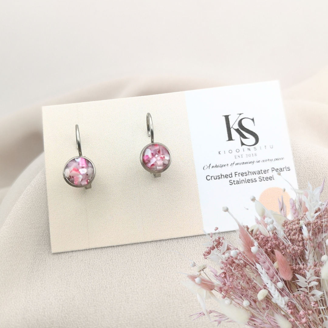 Handmade with care, these 6 mm stainless steel leverback earrings feature crushed freshwater pearls in soft pink tones, sealed beneath a glass-like resin that highlights their natural shimmer.