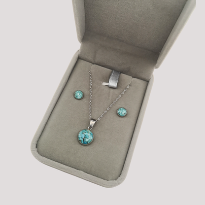 Jewelry set with turquoise stones in an open jewelry box on a light gray background