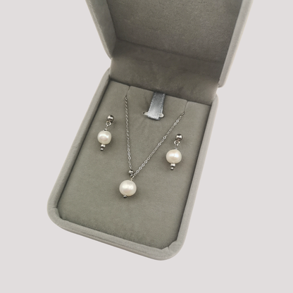 Pearl necklace and earrings set in a jewelry box on a light gray background