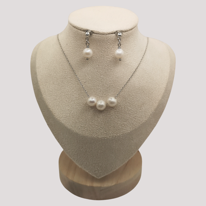 Pearl necklace and earrings set on a mannequin bust against a white background
