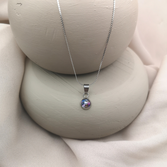 An 8 mm stainless-steel round pendant cradles crushed freshwater pearls, glowing with soft iridescent hues like petals kissed by fading light