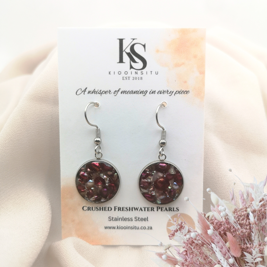Handmade with care, these earrings feature crushed freshwater pearls in rich crimson and iridescent tones, set within 16 mm stainless steel bezels and sealed beneath a clear, glass-like resin.