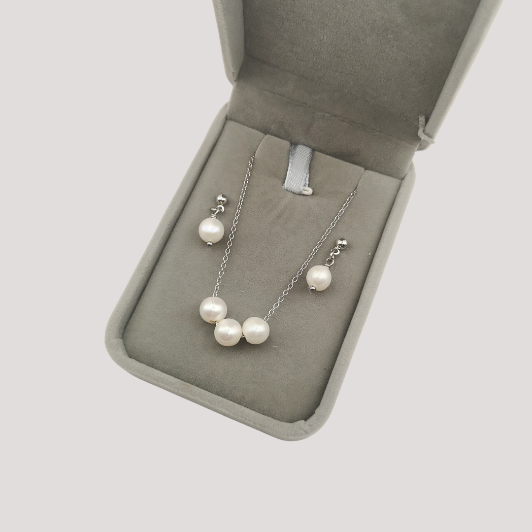 Pearl necklace and earrings set in a jewelry box on a light gray background