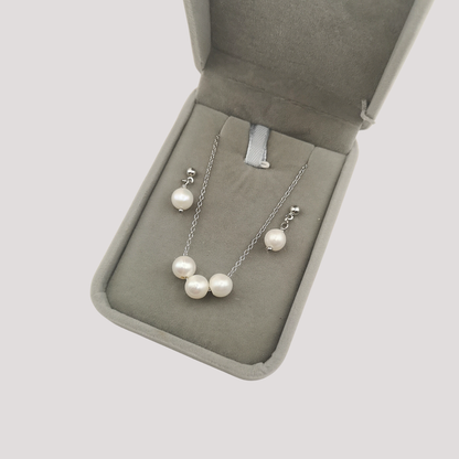 Pearl necklace and earrings set in a jewelry box on a light gray background
