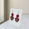 Handmade dark maroon and gold layered teardrop polymer clay dangle earrings on white display stand
