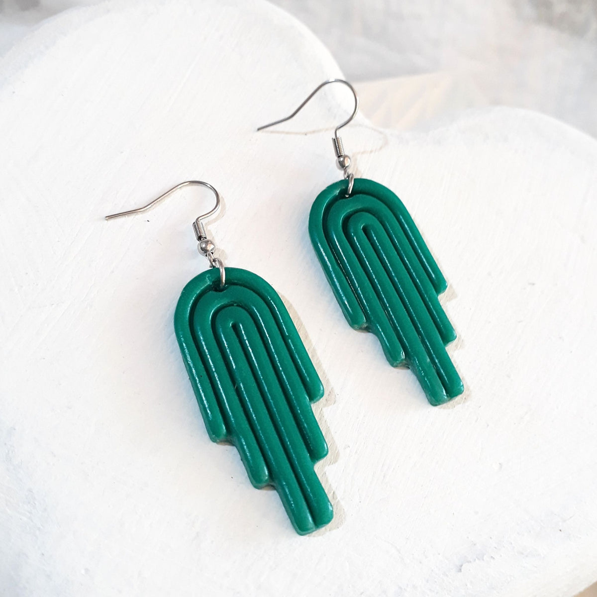 Glossy jade-green polymer clay stepped arch earrings with curved line detailing and silver-tone shepherd ear hooks.