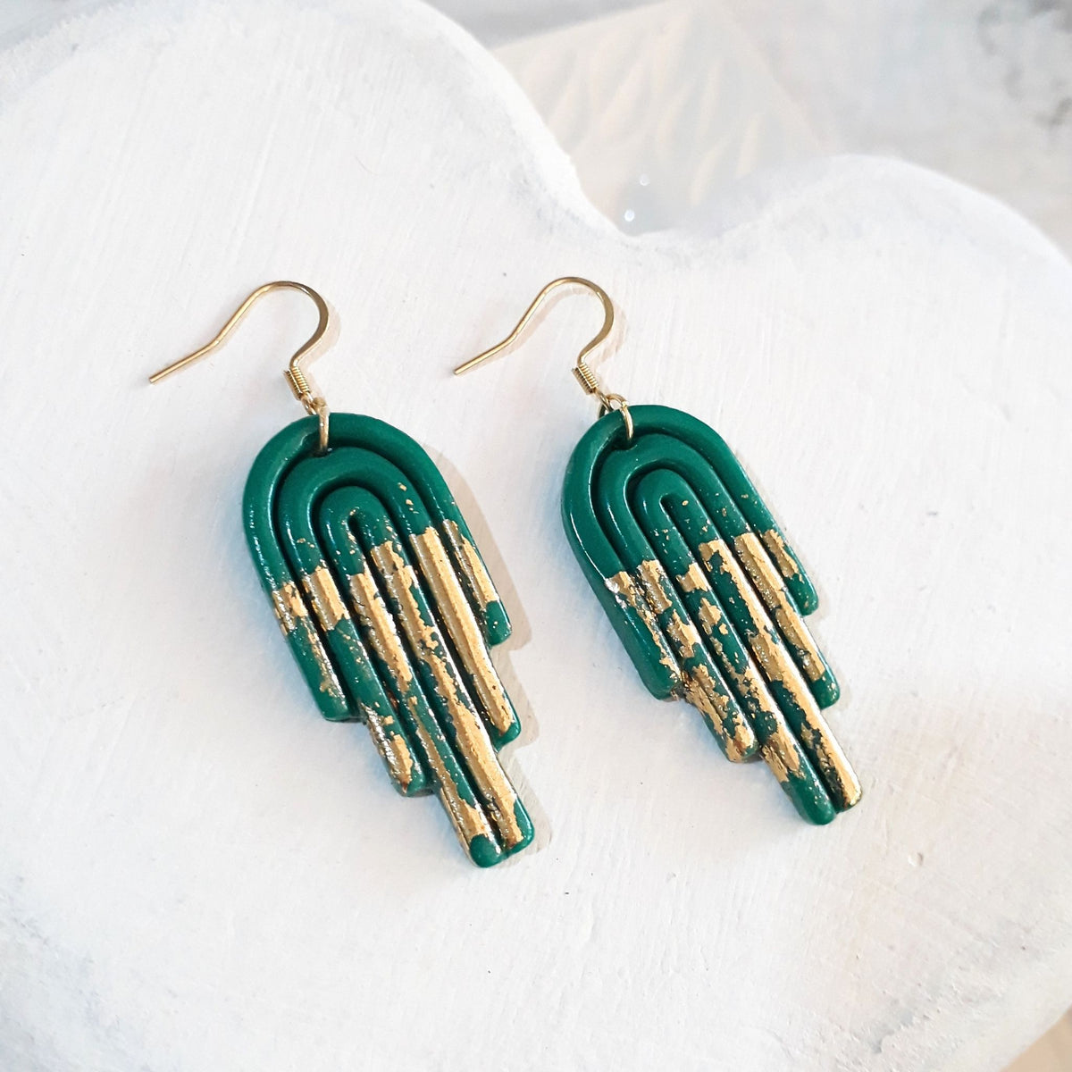 Jade-green glossy polymer clay stepped arch earrings with gold-coloured accents along the lower curves and gold-tone shepherd hooks.