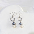 Midnight blue and white freshwater pearl drop earrings with open silver-tone hexagon connectors and shepherd ear hooks.
