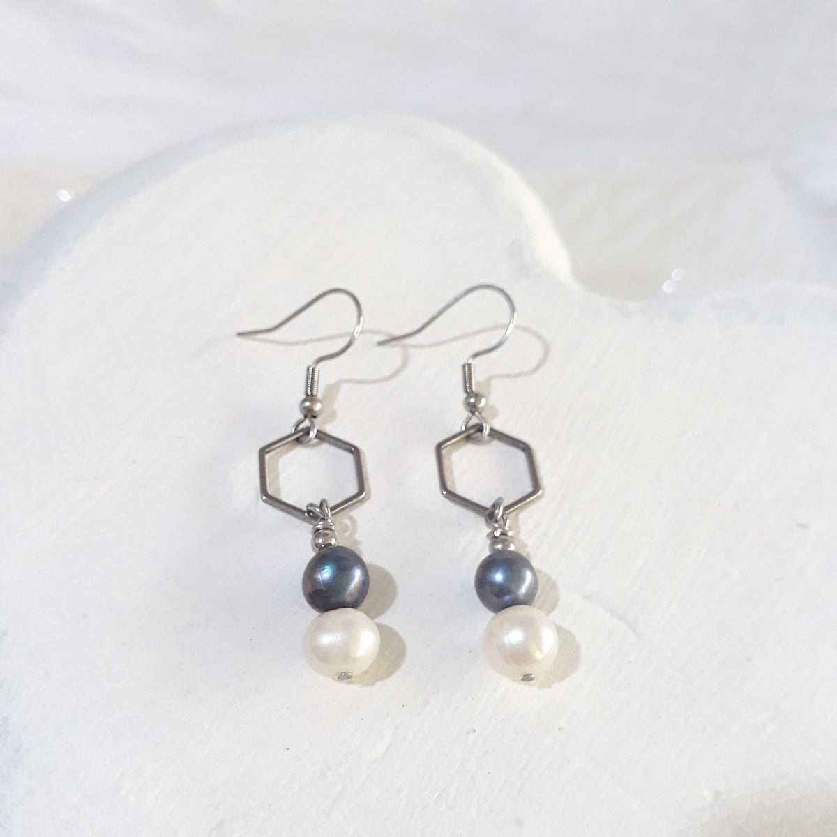 Midnight blue and white freshwater pearl drop earrings with open silver-tone hexagon connectors and shepherd ear hooks.
