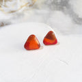 Glossy rounded triangle polymer clay stud earrings with orange, warm brown and deep red colour patches.