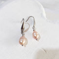 Peach-pink pear-shaped freshwater pearl drop earrings with silver-tone elegant ear hooks.