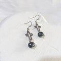 Dark peacock freshwater pearls suspended beneath open silver-tone crosses on stainless steel ear hooks.