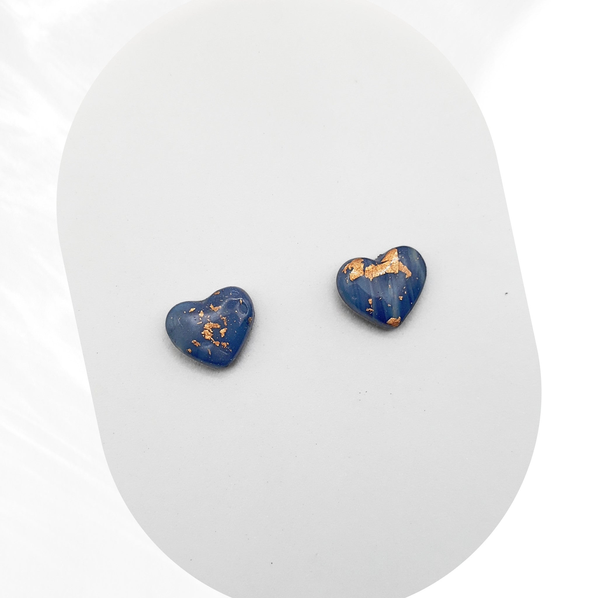 Heart-shaped blue earrings with gold accents on a white background