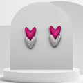 Heart-shaped earrings with pink hearts and silver bases on a gray stand.