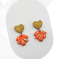 Heart-shaped earrings with orange and gold leaf designs on a white background