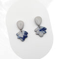 Pair of earrings with blue and gray stone-like pendants on a white background