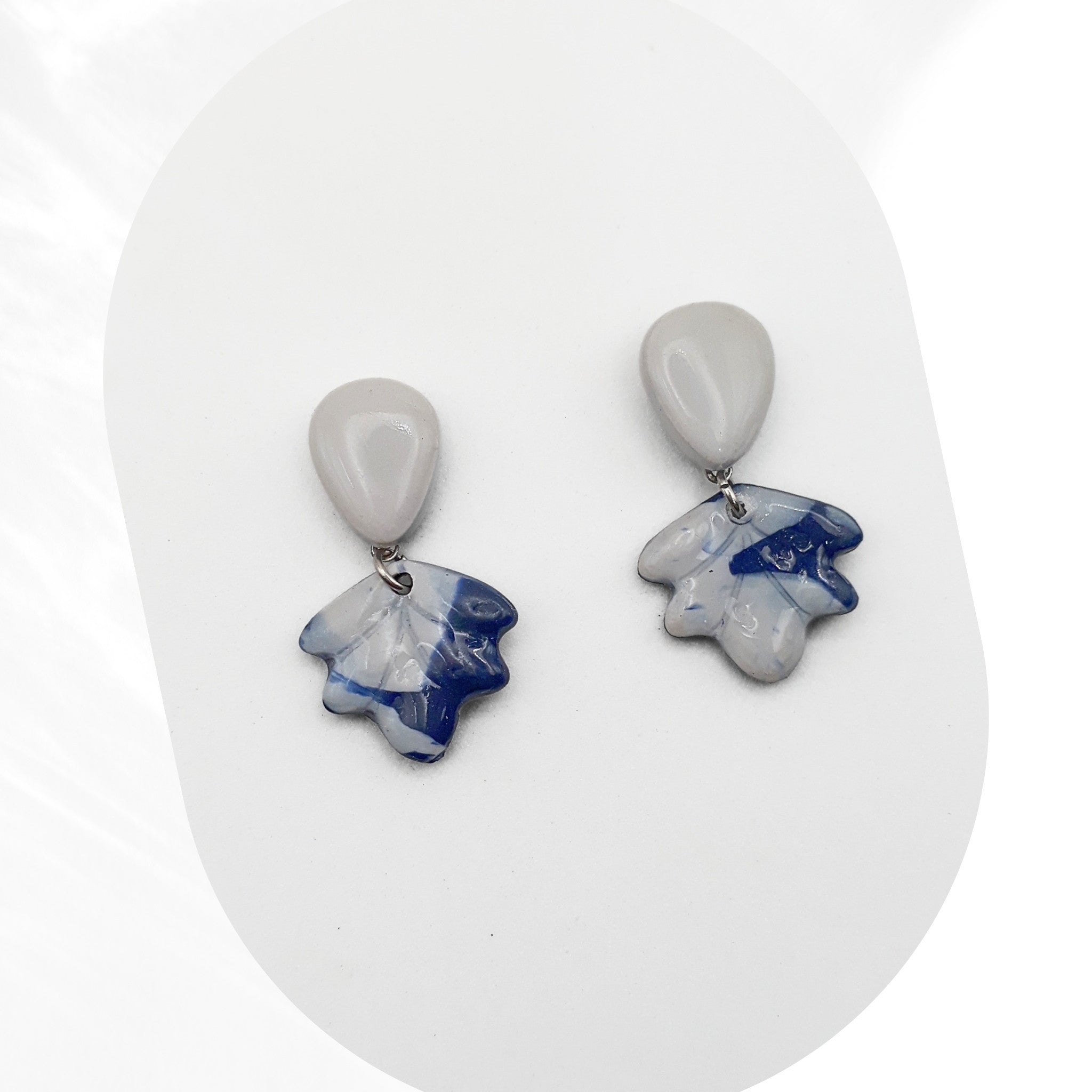 Pair of earrings with blue and gray stone-like pendants on a white background