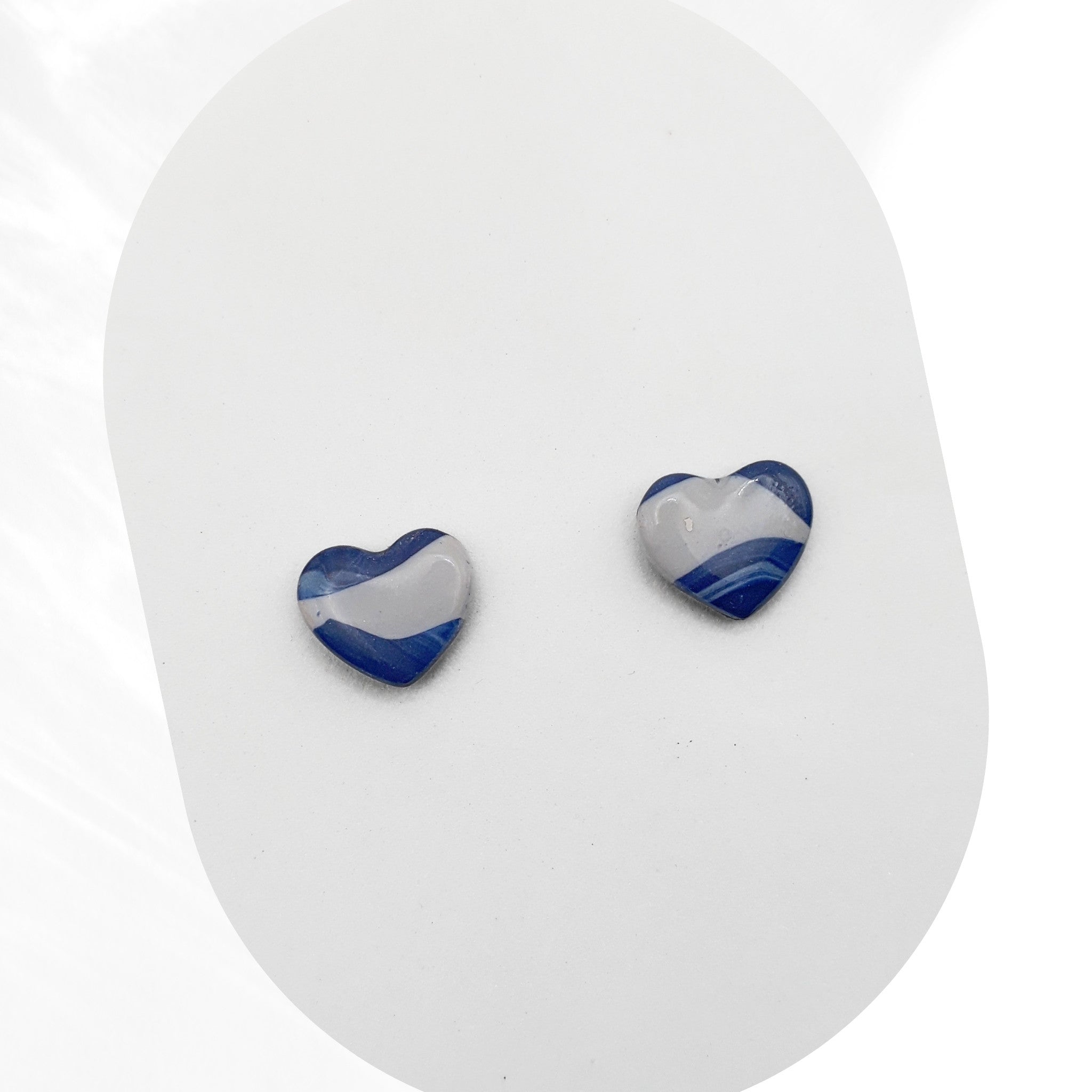 Heart-shaped blue and gray polymer clay earrings on a white background