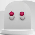 Heart-shaped earrings with red top and silver bottom on a white stand.