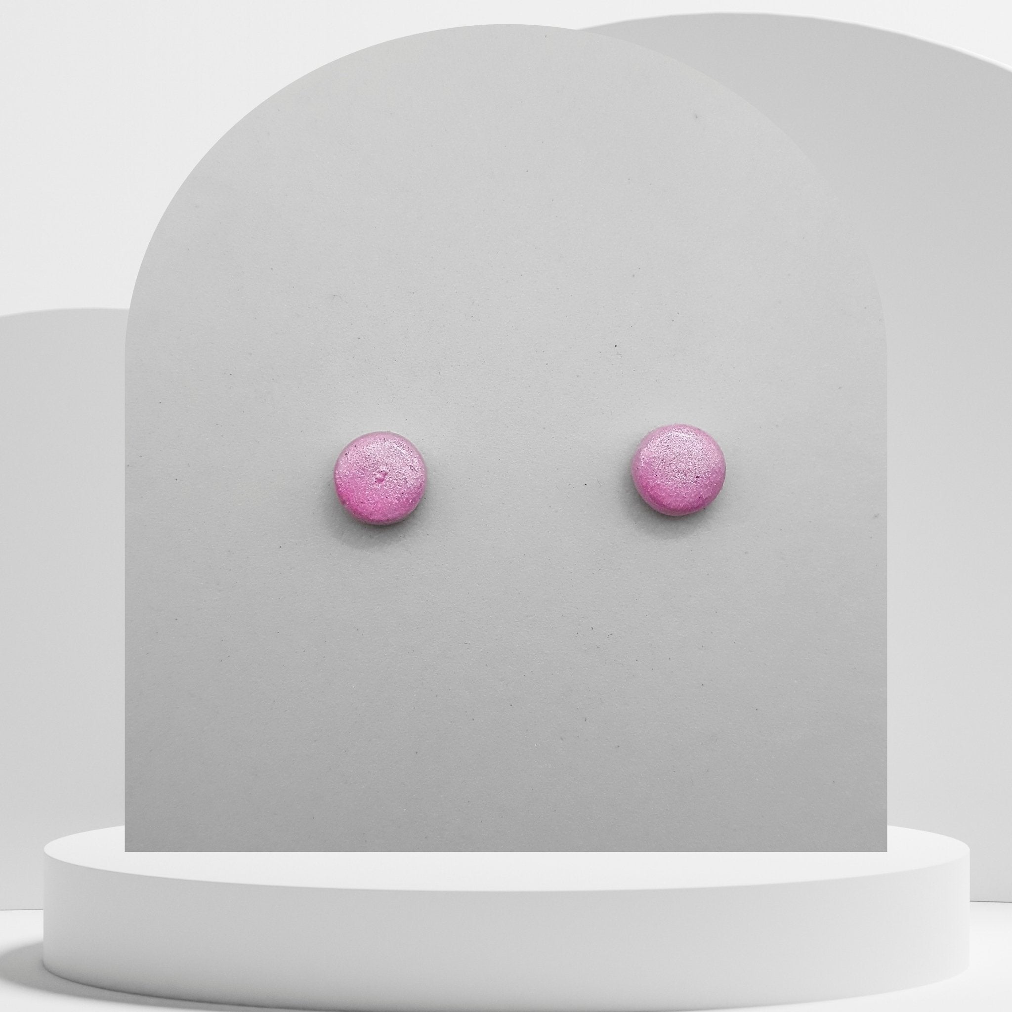 Pink stud earrings on a gray card with a white background