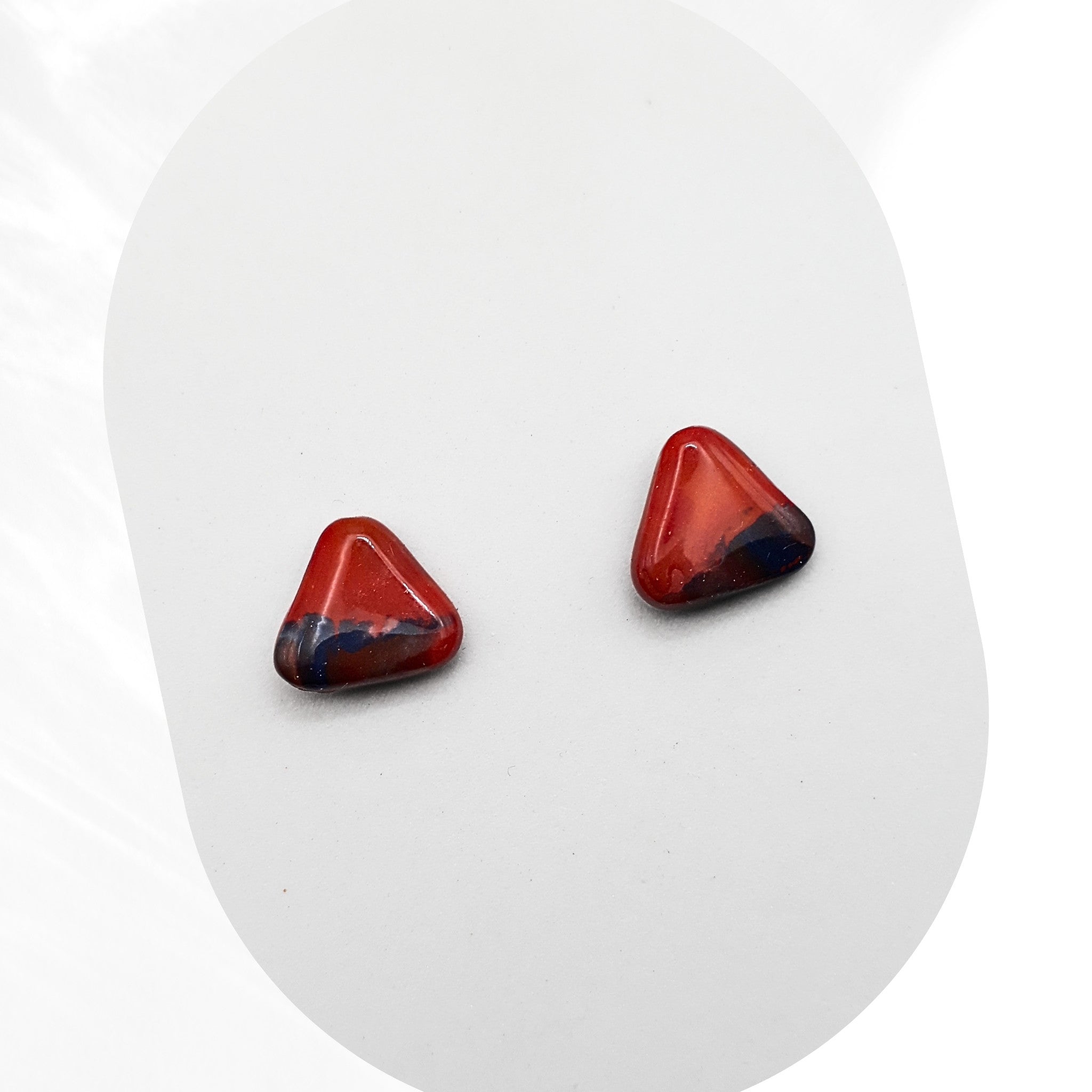 Pair of red triangular earrings on a white background