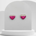 Heart-shaped earrings with pink and gold design on a white stand