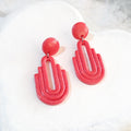 Handmade salmon pink Art Deco arch cutout polymer clay drop earrings on white display tray