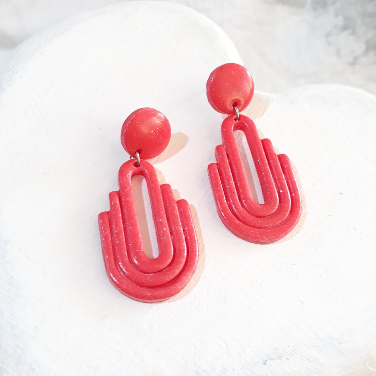 Handmade salmon pink Art Deco arch cutout polymer clay drop earrings on white display tray