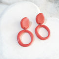 Glossy salmon-pink polymer clay earrings with off-round stud tops and dangling open off-round hoops.