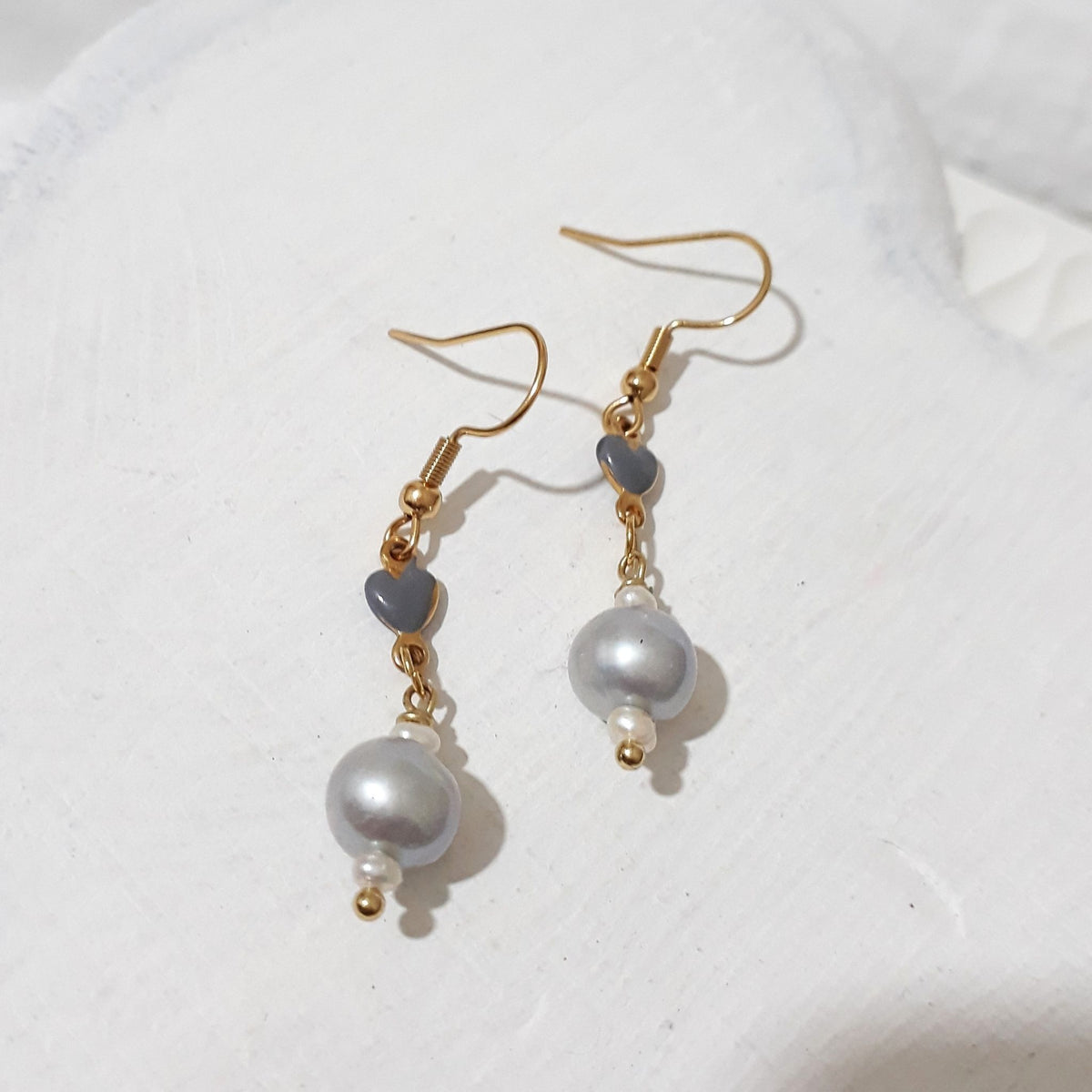 Silver freshwater pearl dangle earrings with grey ceramic hearts, small white bead accents and gold-tone shepherd hooks.