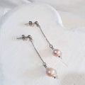 Soft pink round freshwater pearls between small white rice pearls, suspended from fine silver-tone chains and ball studs.