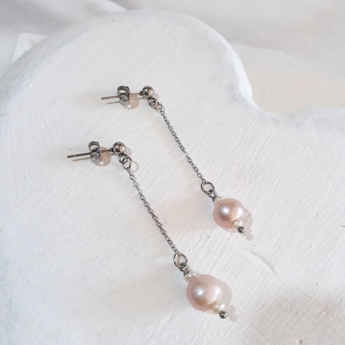Soft pink round freshwater pearls between small white rice pearls, suspended from fine silver-tone chains and ball studs.
