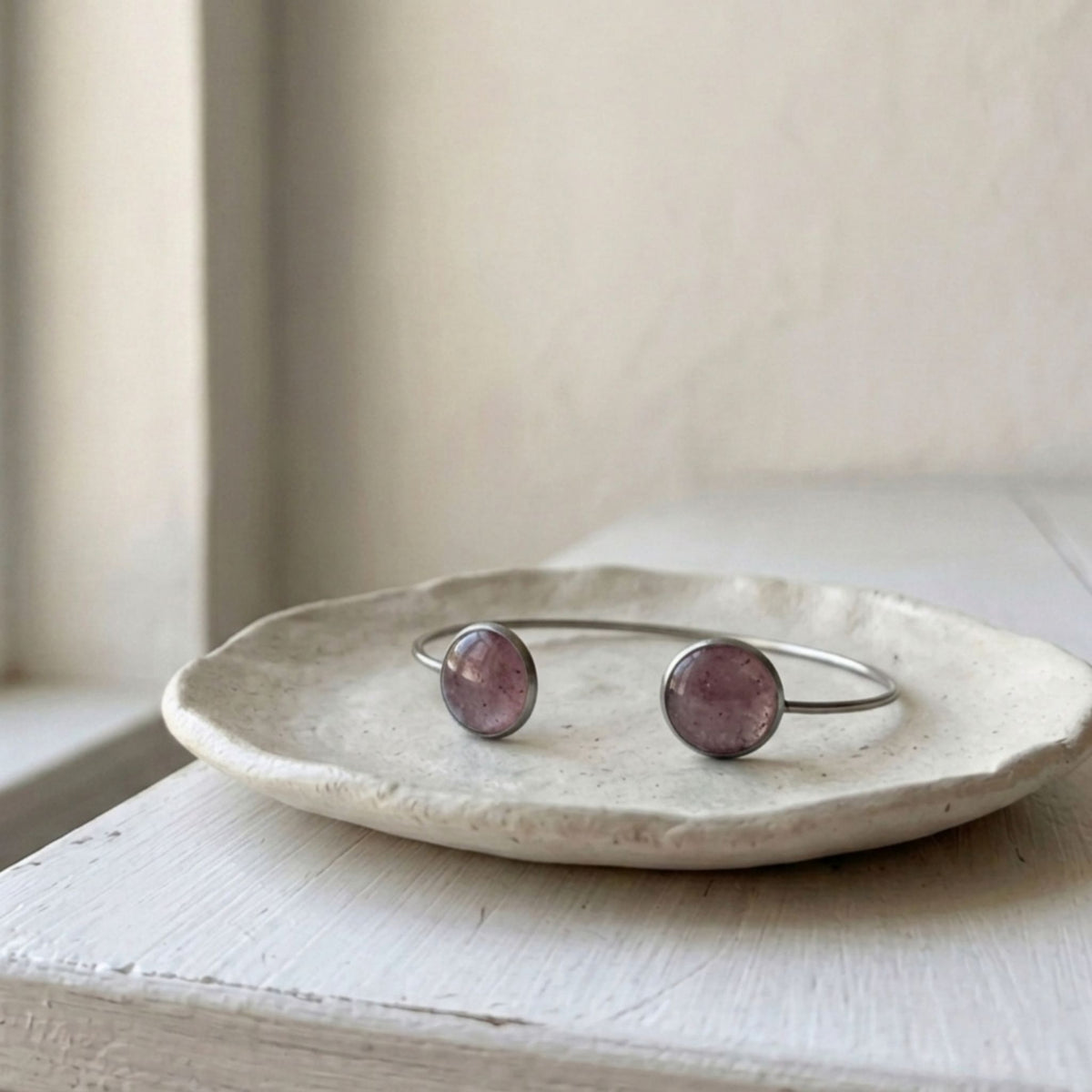 Handcrafted with a sleek stainless steel open cuff design, this elegant bangle features two round bezels filled with natural crushed Pink Aura Quartz - Kiooinsitu