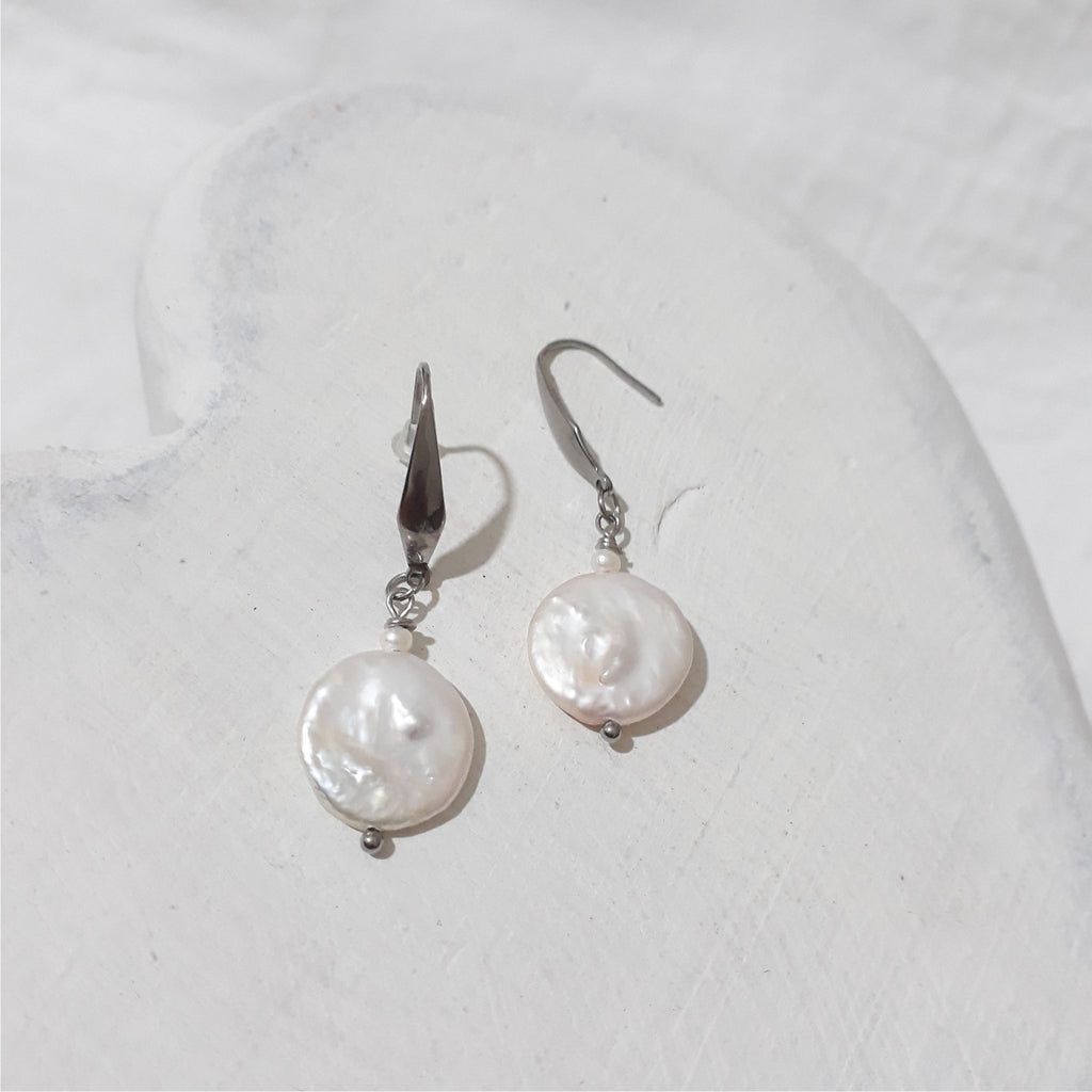 White freshwater coin pearl drop earrings with small white rice pearls above the coin pearls and stainless steel elegant hooks.
