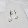 White freshwater coin pearl drop earrings with small white rice pearls above the coin pearls and stainless steel elegant hooks.