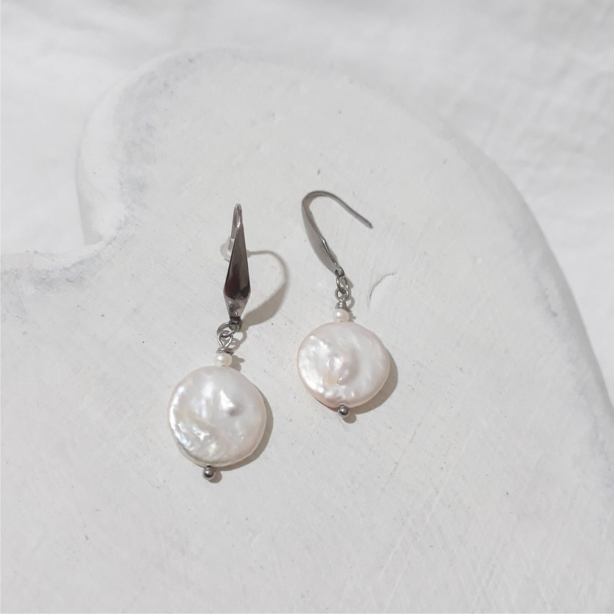 White freshwater coin pearl drop earrings with small white rice pearls above the coin pearls and stainless steel elegant hooks.