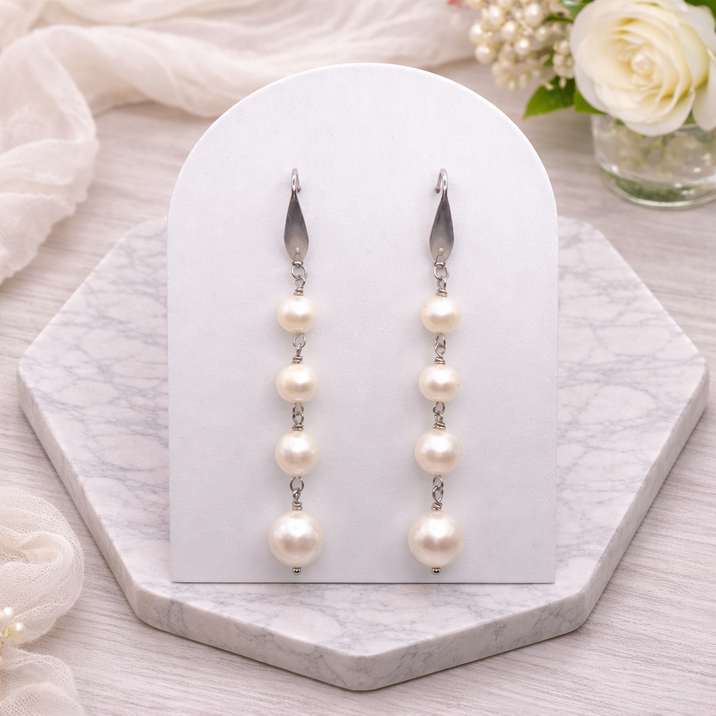 Cascade white Pearl earrings on a white card with a soft floral background