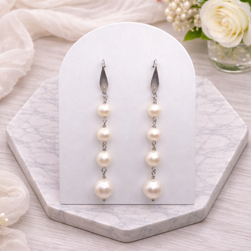 Cascade white Pearl earrings on a white card with a soft floral background