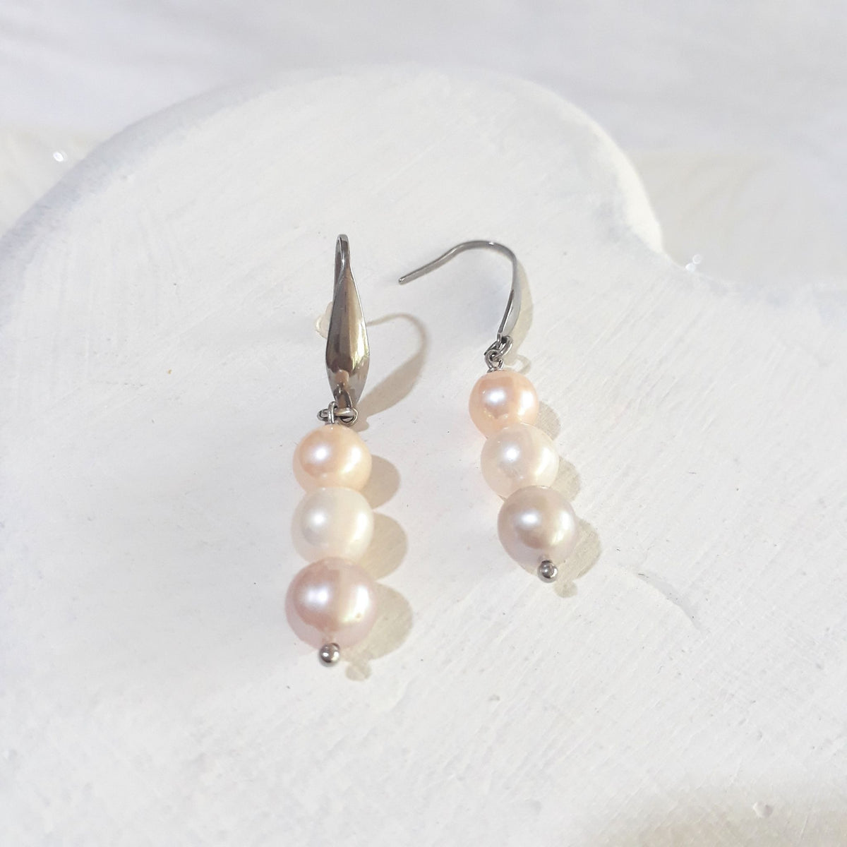 Triple freshwater pearl drop earrings with peach-pink, creamy white and soft lavender pearls on silver-tone elegant ear hooks.