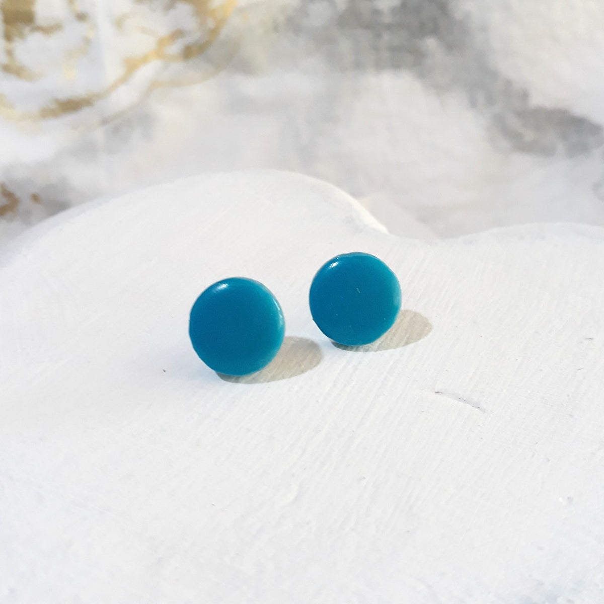Pair of turquoise round polymer clay stud earrings with smooth glossy surfaces.