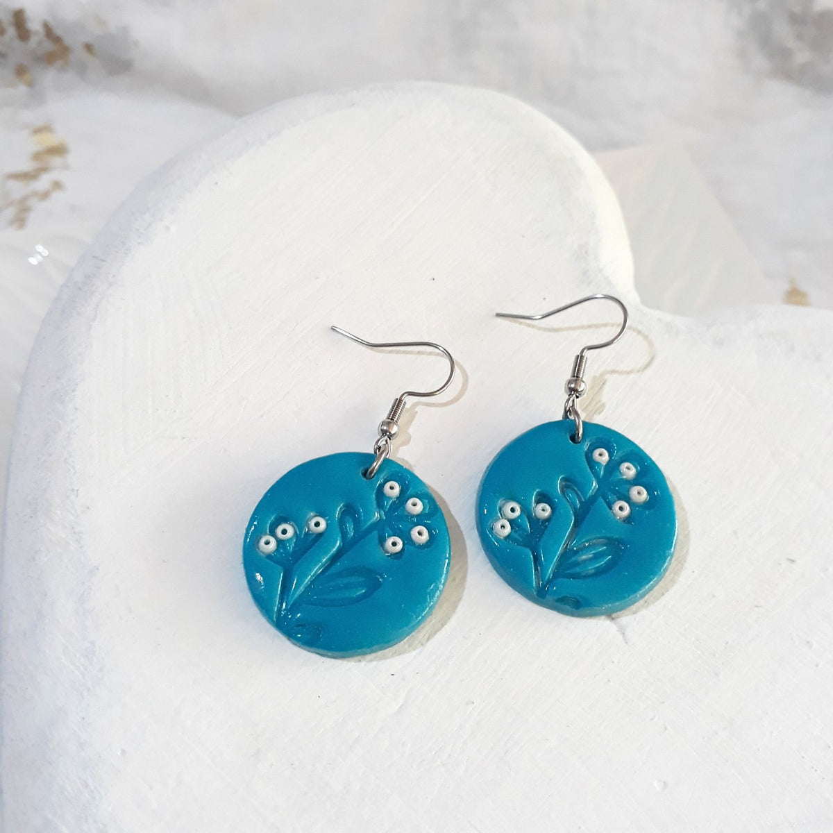 Turquoise round polymer clay drop earrings with leafy stem detailing, small white bead accents and silver-tone shepherd hooks.