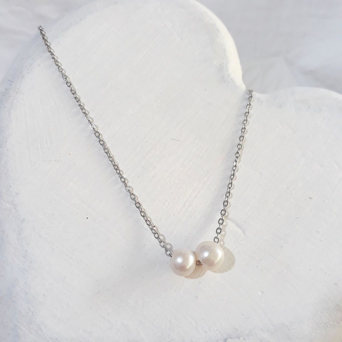 Two freely floating freshwater pearls on a stainless steel chain