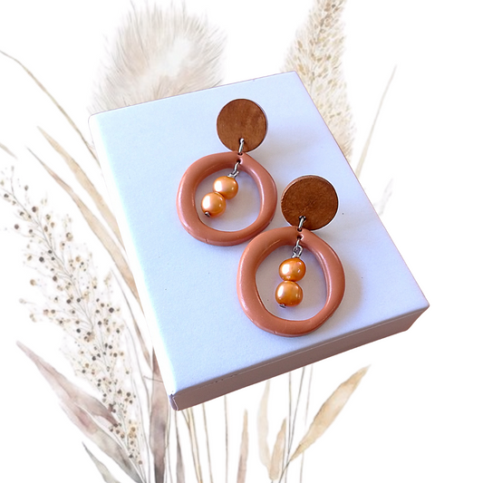 Indulge in the exquisite elegance of our Polymer Clay &amp; Freshwater Pearl Hoop Earrings. Handmade with stunning Golden orange freshwater pearls, these earrings feature salmon pink polymer clay hoops and walnut wood ear studs with a stainless steel pin.