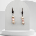 Pair of pearl earrings on a white stand with a plain background