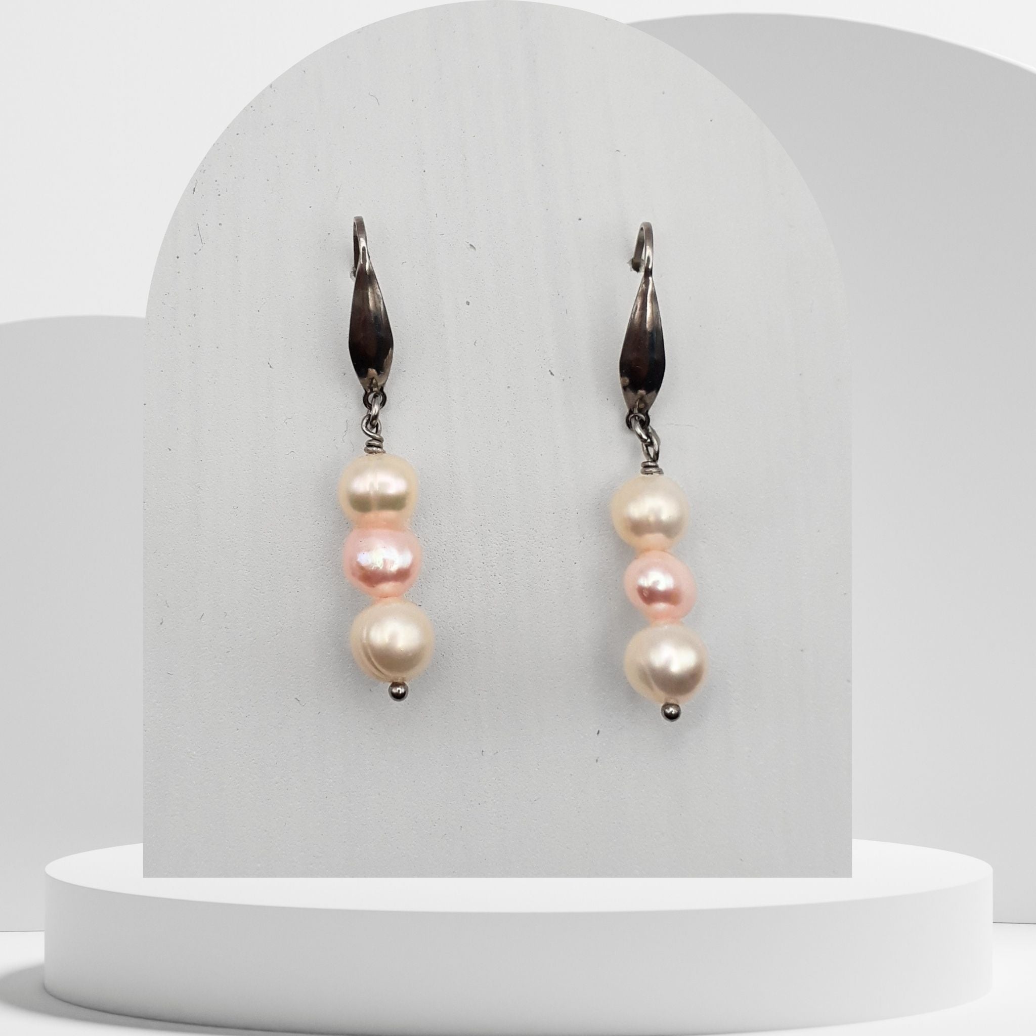 Pair of pearl earrings on a white stand with a plain background