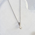 Small white freshwater pearl pendant with a silver-tone bail on a stainless steel chain, displayed against a white background.